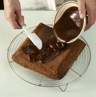 Pâtissier nappant un gâteau avec du chocolat - Crédits : Adobe Stock/FOOD-micro